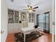 Bright home office with built-in bookcases, hardwood floors, a ceiling fan, and natural light from a window at 10230 Barrington Ct, Leesburg, FL 34788