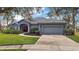 Inviting single-story home showcasing lush landscaping, a two-car garage, and an attractive red front door at 10606 Masters Dr, Clermont, FL 34711