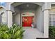 Covered front porch with decorative red door framed by white columns and lush landscaping at 10606 Masters Dr, Clermont, FL 34711