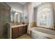 Elegant bathroom featuring a soaking tub, shower and vanity with a marble countertop at 10606 Masters Dr, Clermont, FL 34711