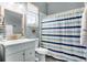 Charming bathroom featuring a vanity with a mirror, toilet and shower with a stylish striped curtain at 11101 Versailles Blvd, Clermont, FL 34711