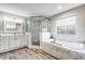 Elegant bathroom with marble tile, soaking tub, glass shower and modern fixtures at 11101 Versailles Blvd, Clermont, FL 34711