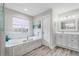 Elegant main bathroom with tub, glass shower, vanity and calming natural light at 11101 Versailles Blvd, Clermont, FL 34711