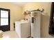 Functional laundry room with washer, dryer, water heater, storage shelf, and access to the exterior via black trimmed door at 1119 Cr 457, Lake Panasoffkee, FL 33538