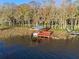 Aerial view of a boat lift on this lakeside property with mature trees and lake views at 11243 Dead River Rd, Tavares, FL 32778