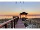 Scenic sunset view from the private boat dock on the water with boat lift, bench, and covered area at 11243 Dead River Rd, Tavares, FL 32778