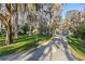 Spacious driveway leading to a cozy home with a lush lawn and mature trees draped in Spanish moss at 11243 Dead River Rd, Tavares, FL 32778