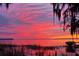 Stunning lake view captures a vibrant sunset over the water, with a silhouette of a boat dock for evening relaxation at 11243 Dead River Rd, Tavares, FL 32778