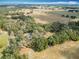 Expansive aerial view of land, with lush trees, open fields, and distant homes under a bright sky at 12220 County Road 209, Oxford, FL 34484