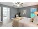 Bedroom with gray walls, ceiling fan, wood floors, and an open bathroom at 12220 County Road 209, Oxford, FL 34484