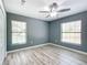 Bedroom with wood-look floors, two large windows, and a ceiling fan at 12220 County Road 209, Oxford, FL 34484