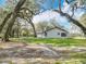 Exterior of home with a lush, expansive lawn and the backdrop of mature, moss-draped trees at 12220 County Road 209, Oxford, FL 34484