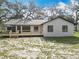 Rear exterior showcasing fresh white paint, dark trim, new backyard deck, and ample yard space at 12220 County Road 209, Oxford, FL 34484