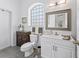 Bathroom featuring a white vanity with a mirror and a corner cabinet, a toilet and glass block window at 12390 Se 176Th Loop, Summerfield, FL 34491