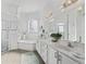 Bright bathroom featuring double sinks, a soaking tub, a glass-enclosed shower, and decorative lighting fixtures at 12390 Se 176Th Loop, Summerfield, FL 34491