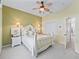 Bright bedroom with white furnishings, light green walls, a ceiling fan, and a closet with double doors at 12390 Se 176Th Loop, Summerfield, FL 34491