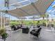 Outdoor patio featuring striped awning, umbrellas, lounge seating, and golf course views perfect for entertaining at 12390 Se 176Th Loop, Summerfield, FL 34491