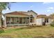 Spacious backyard featuring a screened-in patio, lush green lawn, and mature trees at 1273 Oak Forest Dr, The Villages, FL 32162