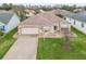 Aerial view showcasing a well-maintained home with a two-car garage and landscaped front yard at 1303 Fontana Ct, Lady Lake, FL 32159