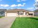 Charming single-story home with a well-manicured lawn, neutral paint, and an attached two-car garage at 1303 Fontana Ct, Lady Lake, FL 32159