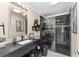 Modern bathroom featuring a sleek black vanity, glass-enclosed shower with decorative tile, and marble-look flooring at 1312 Patrick Pl, The Villages, FL 32162