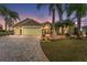 Dusk view of single-Gathering home featuring stone accents, lush landscaping, a paver driveway, and a red front door at 1312 Patrick Pl, The Villages, FL 32162
