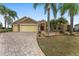 Beautiful home exterior with manicured lawn, stone accents, brick driveway, and a two-car and one-car garage at 1312 Patrick Pl, The Villages, FL 32162