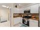 Bright kitchen features white cabinets, stainless steel appliances, and granite countertops with a stylish tile backsplash at 1312 Patrick Pl, The Villages, FL 32162