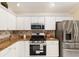 Close-up of kitchen featuring stainless steel appliances, granite countertops, white cabinets, and a tile backsplash at 1312 Patrick Pl, The Villages, FL 32162
