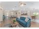 Open-concept living room showcasing wood floors, a blue sofa, and an open view to dining and kitchen spaces at 1312 Patrick Pl, The Villages, FL 32162
