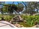 Landscaped lanai with a charming waterfall and pond, creating a peaceful outdoor retreat at 1312 Patrick Pl, The Villages, FL 32162