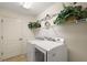 Well-lit laundry room with white washer, dryer and storage shelves at 1339 Florence Path, The Villages, FL 32162