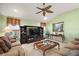 Comfortable living room with carpet flooring, ceiling fan, and a large entertainment center for storage and display at 1339 Florence Path, The Villages, FL 32162