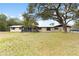 Tan home featuring a metal roof, a porch with black trim, and a large front yard with mature trees at 14100 Ne 46Th St, Silver Springs, FL 34488