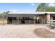 Equestrian shelter with sand ground, metal roof, wooden stalls and gates, with the home in the background at 14100 Ne 46Th St, Silver Springs, FL 34488