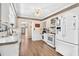 Classic kitchen with white cabinets and appliances, complemented by wood-look flooring and neutral walls at 14100 Ne 46Th St, Silver Springs, FL 34488