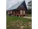 This exterior shot highlights a rustic, two-story cabin with a covered porch and stone foundation at 14415 County Road 448, Tavares, FL 32778