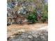 A partial exterior view of the home is framed by mature trees and colorful landscaping at 14415 County Road 448, Tavares, FL 32778