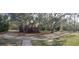 View of the front yard featuring flowering shrubs, trees, and a long driveway at 14415 County Road 448, Tavares, FL 32778