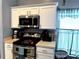 Kitchen with stainless steel appliances, white cabinets, and checkered curtains at 16705 Rolling Green Dr, Clermont, FL 34714