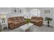 Comfortable living room featuring cozy brown sofas, a modern coffee table, and bright natural light from the sheer curtained windows at 16726 Hidden Spring Dr, Clermont, FL 34714