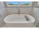 Stylish soaking tub with modern fixtures and a view from the bathroom window at 1679 E County Road 462, Wildwood, FL 34785