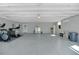 Expansive garage with epoxy flooring offers versatile space for vehicles, storage, and recreational activities, featuring abundant lighting at 1679 E County Road 462, Wildwood, FL 34785