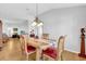 Open-concept dining area with a wooden table, red leather chairs, and modern chandelier at 17979 Se 89Th Rothway Ct, The Villages, FL 32162