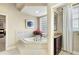 Bright bathroom featuring a tiled corner tub with glass block window and dark wood vanity with marble countertop at 2059 Landings Ln, The Villages, FL 32162