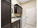 Modern laundry room equipped with black cabinets, granite countertop sink, and white washer and dryer at 2059 Landings Ln, The Villages, FL 32162