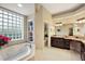 Bathroom featuring a soaking tub by a glass block window and vanity at 2059 Landings Ln, The Villages, FL 32162