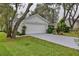 Two-car garage with white door, surrounded by mature trees and green lawn at 210 Palermo Pl, Lady Lake, FL 32159