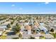 An aerial view of a home with blue awnings in a lively residential community under a bright blue sky at 2495 Birch Ave, The Villages, FL 32162