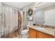 Well-lit bathroom features a granite vanity top, framed mirror, and decorative shower curtain at 2495 Birch Ave, The Villages, FL 32162